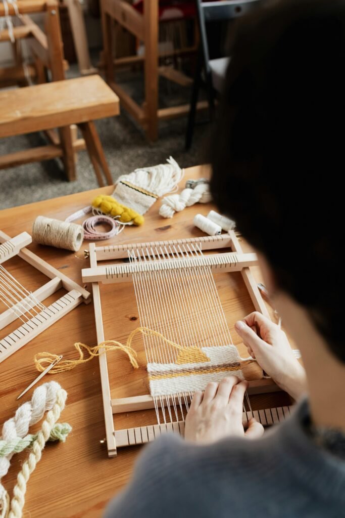 pexels photo 4219656 4219656 A craftsman skillfully weaves on a hand loom at a wooden table indoors.