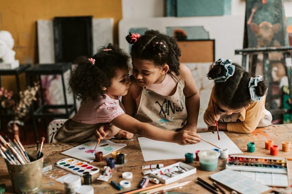 pexels photo 7025968 7025968 Three children engaged in an art activity, painting together with watercolors and brushes.